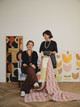 Michal Silver, Creative Director of Christopher Farr Cloth, with artist Véronique de Soultrait, presenting the Atelier Véronique Collection. The image features original embroidered artwork by Véronique alongside a quilt and an upholstered chair showcasing fabrics from the collection.